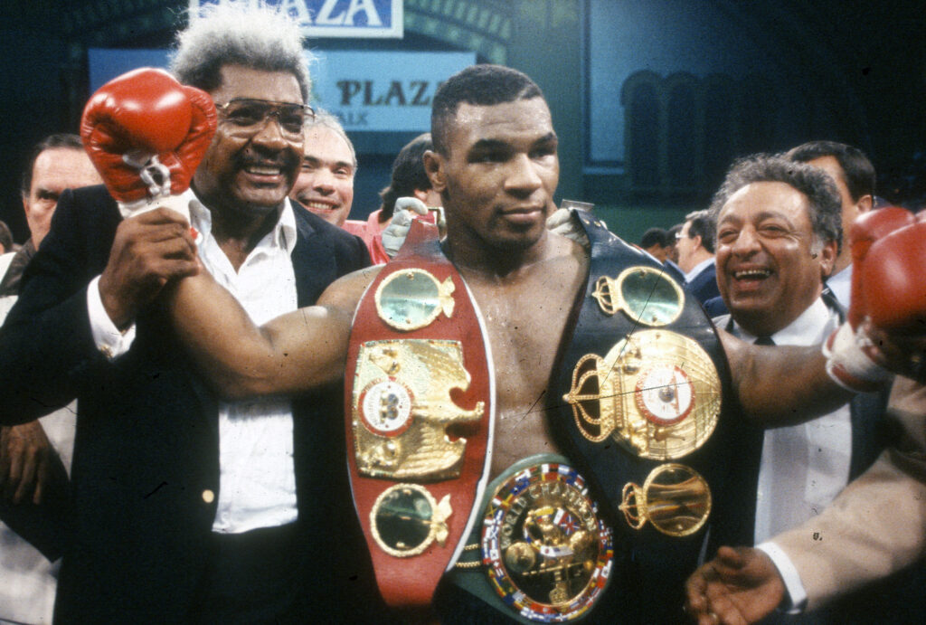 Mike Tyson poses with his world title belts alongside Don King after knocking out Carl Williams
