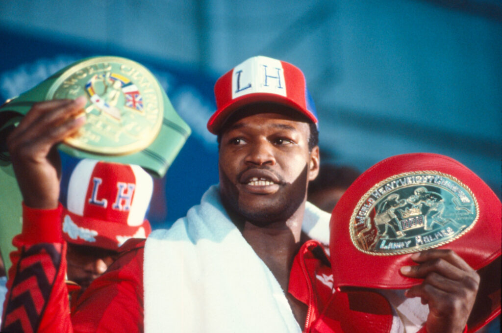 Larry Holmes raises his belts during his pre-fight press conference ahead of his heavyweight fight with Muhammad Ali in 1980