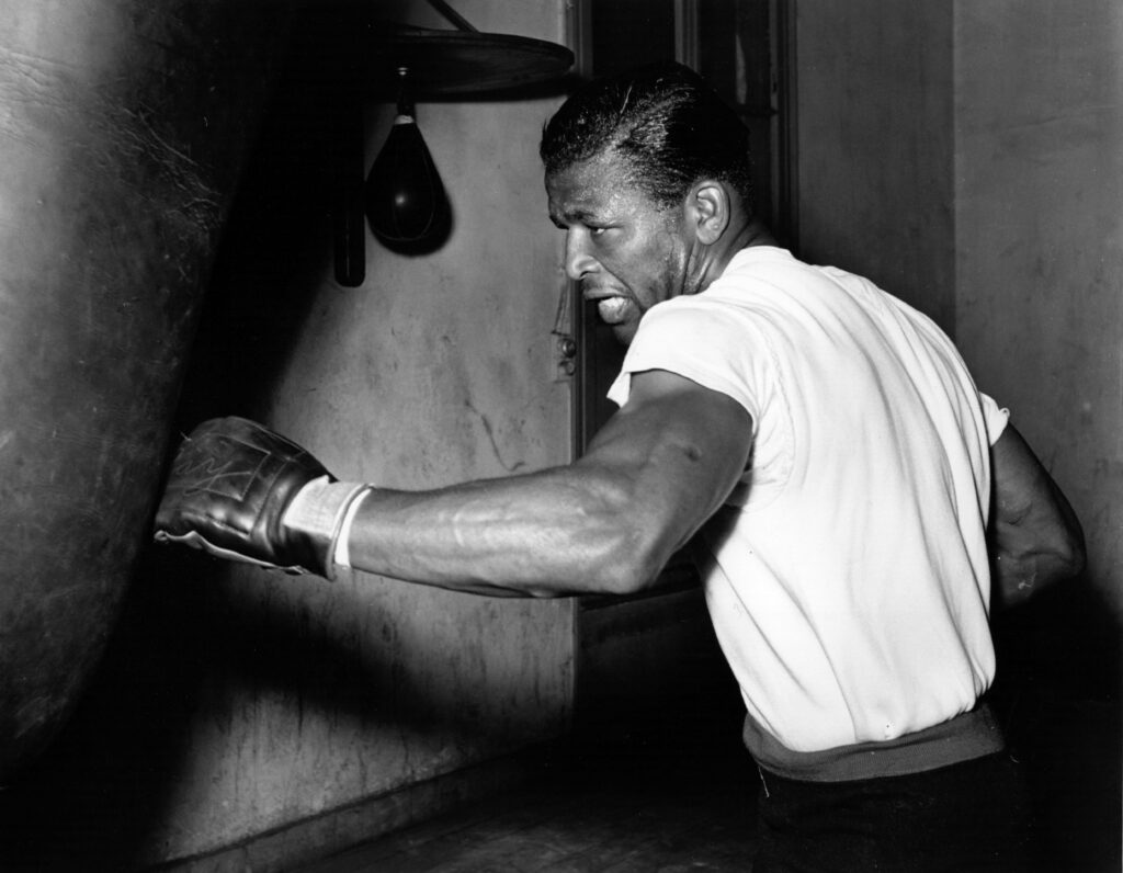 Sugar Ray Robinson attacks a heavy bag during a boxing training session
