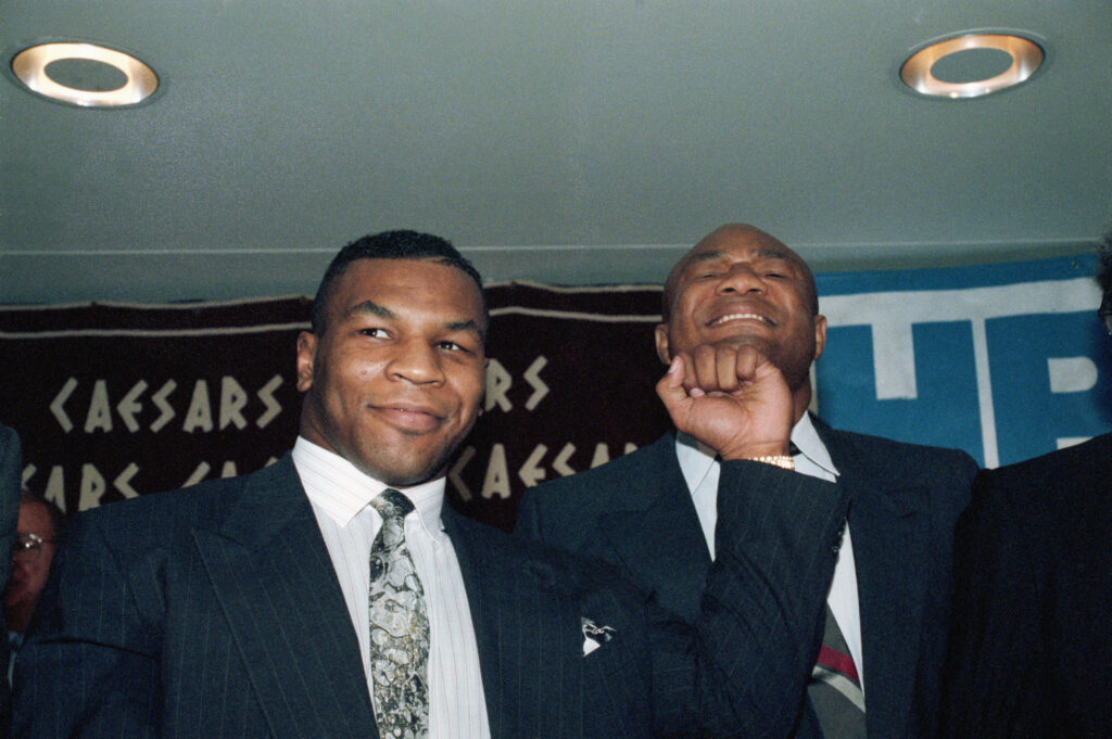 Mike Tyson pretends to punch George Foreman at a press event in 1990
