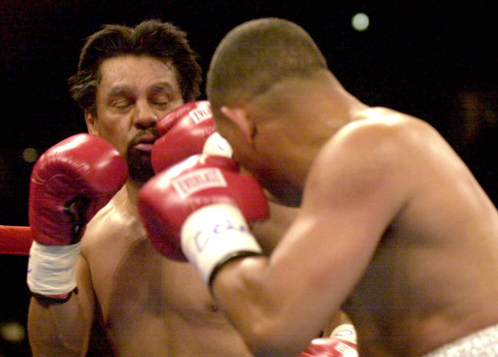Roberto Duran blocks a punch thrown by Hector Camacho in their rematch fight at the Pepsi Center in 2001